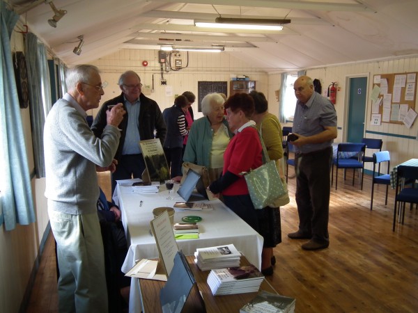The author and  a group of people chatting inside the village hall