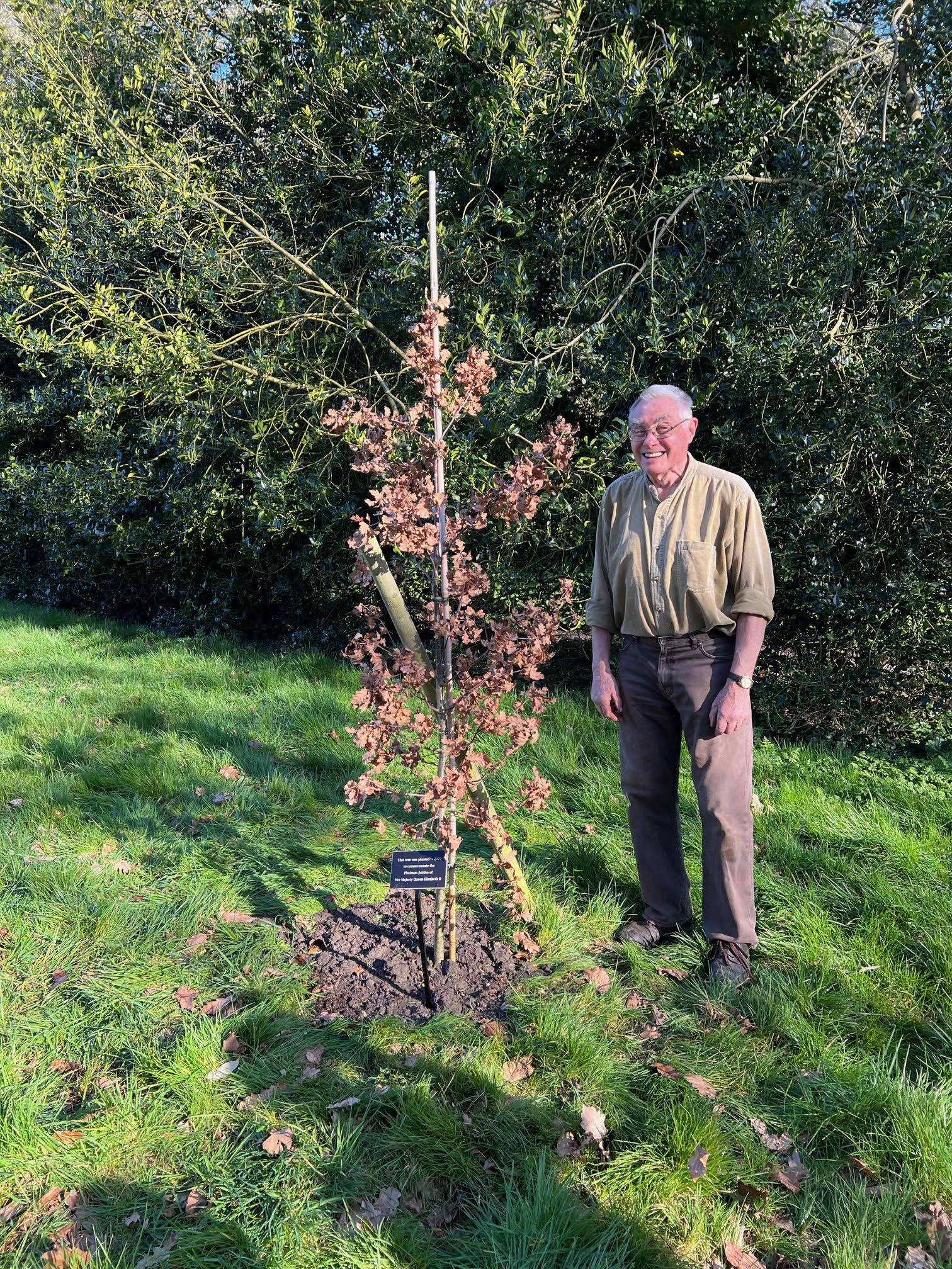 Roger Coates-Smith standing next to the newly planted Jubilee tree